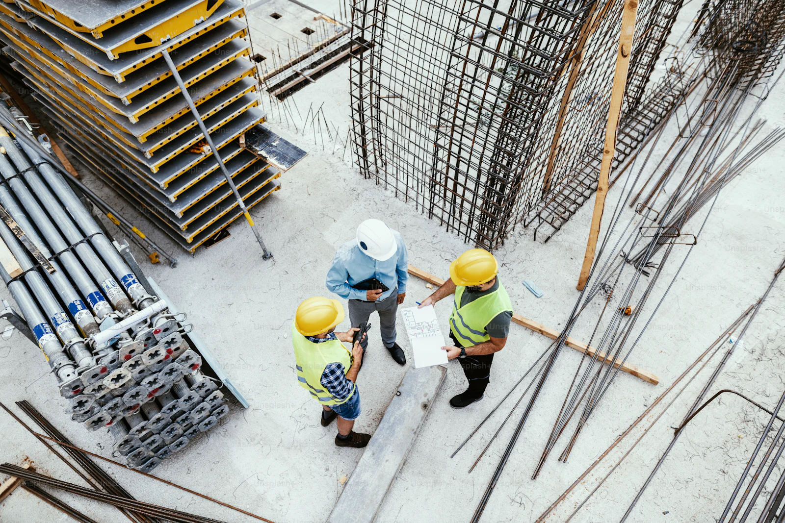Close-up of construction workers' hands with tools and blueprints, symbolizing precision and planning.